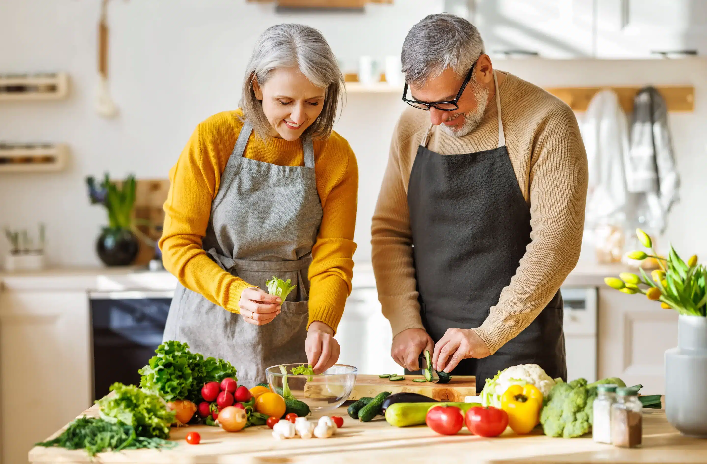 Woman and man in kitchen chopping vegetables